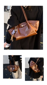 Detail of brown pleated leather tote bag with elegant straps and decorative charm