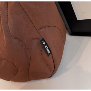 Detailed view of coffee brown quilted wave pattern fabric with woven brand tag detail