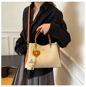 Détail du sac bandoulière bicolore avec breloque coeur et logo kangourou devant