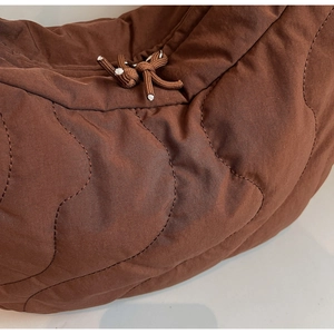 Detail of brown quilted bag showing wave stitching and soft down-like texture decoration