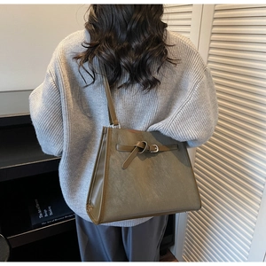 Gros plan sur un sac cabas vert armée en cuir mat avec boucles à sangles stylées