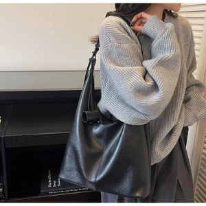 Close-up of a black large capacity leather tote bag worn by a model for daily commuting