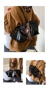 Detail of black glossy tote bag with pleated sides and leopard heart charm