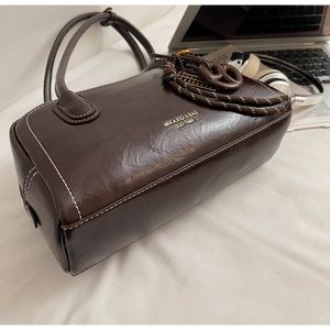 Détail du sac boston rétro marron en cuir avec coutures blanches et logo doré