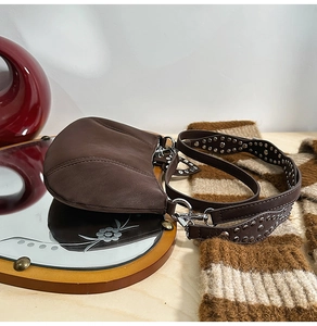 Detail of brown leather hobo bag with vintage silver studs on a wide shoulder strap