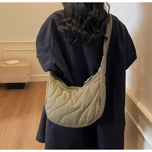 Close-up of lightweight quilted crescent bag in sage green showing wavy texture