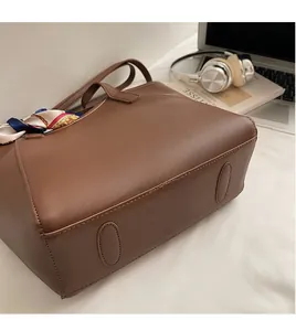 Detailed view of brown leather tote bag with a decorative floral silk scarf on the handle