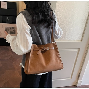Détail du sac cabas en daim marron caramel avec boucle décorative et intérieur spacieux