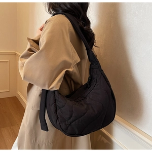 Side view of black quilted puffer crescent bag on model for casual commuting