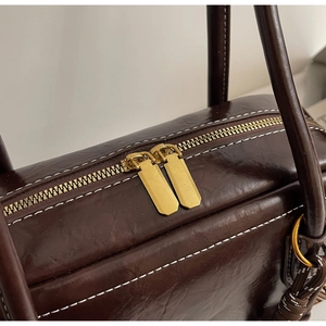 Détails du haut du sac marron vintage avec double fermeture éclair dorée et coutures blanches