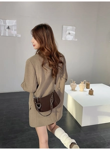 Detail of dark brown leather shoulder bag with studded strap and heart charm