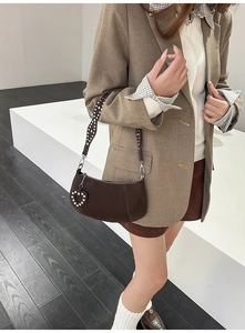 Detail of dark brown leather dumpling bag with polka dot strap and heart diamond pendant