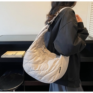 Detail of off-white quilted puffer bag with wave stitching and wide shoulder strap