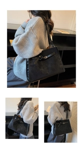Detail of a black matte tote bag featuring decorative metal buckle straps and soft texture