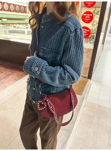 Detail of burgundy hobo bag with silver studs and heart charm worn by a model