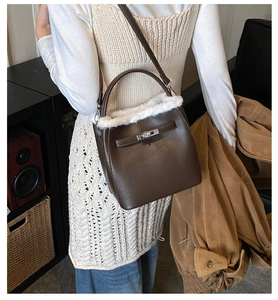 Detail of a brown leather bucket bag with white faux fur trim and silver turn-lock clasp
