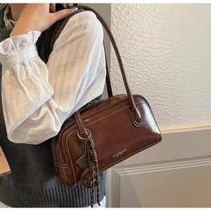 Détail du sac bandoulière vintage marron foncé avec surpiqûres blanches et logo de marque