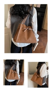 Detail of a brown suede tote bag with decorative buckle and dual straps in a modern room