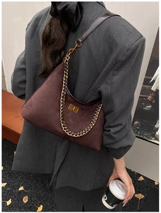Détail du sac sous le bras en daim marron foncé mat avec fermoir doré et chaîne rétro