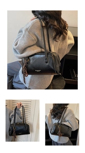 Détail du sac en cuir froissé noir brillant avec coutures blanches et pompon décoratif