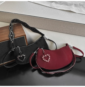 Detail view of rivet-studded straps on matte black and burgundy dumpling bags