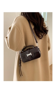 Close-up of a dark brown glossy leather mini bag with a silver H-buckle and long tassels