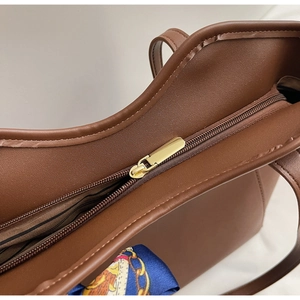 Detailed top view of brown tote bag with gold zipper and striped interior lining
