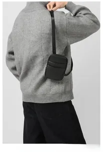 Detail of black pebbled leather crossbody phone bag with card slots and metal zipper