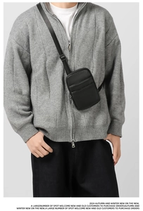 Close-up of black lychee-textured faux leather crossbody bag with silver metal zipper details
