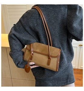 Detail of vintage brown suede underarm bag with smooth leather trim on a knitted sweater