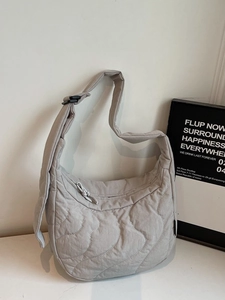 Light grey quilted puffer crossbody bag with wave stitching and adjustable wide strap