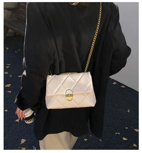 Close-up of cream quilted crossbody bag with gold chain and metal clasp detail