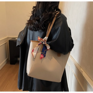 Detail of cream leather tote bag with elegant silk scarf and brown edge stitching