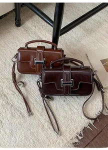 Detail of glossy leather handbags with metal buckles and braided shoulder straps