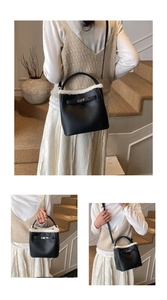 Detail view of black pebbled leather bucket bag with white faux fur trim and metal buckle