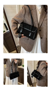 Detail of black suede shoulder bag with glossy patent leather handles and heart charm