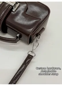 Detail view of dark brown PU crossbody bag featuring custom hardware and detachable strap
