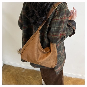 Detail of a brown suede vintage bucket bag with adjustable leather strap and brass buckle