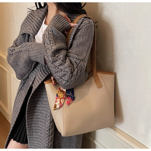 Beige tote bag with brown leather handles and a decorative silk scarf on the strap
