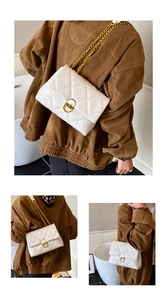 Detail of white quilted crossbody bag with gold-tone metal lock and chain strap