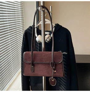 Macro shot of burgundy matte faux suede shoulder bag with heart pendant detail