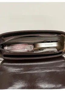 Detail view showing interior capacity of a brown crossbody bag with daily essentials