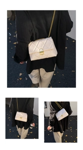 Detail of cream white quilted crossbody bag featuring a round gold lock and chain strap