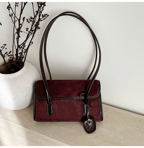 Macro detail of wine red suede and smooth leather texture on elegant shoulder bag