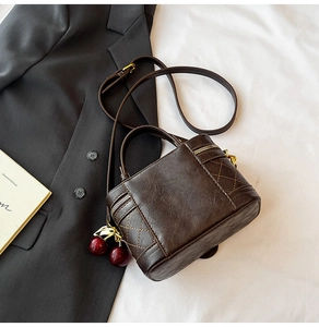 Détail du sac vintage marron matelassé avec fermeture dorée et pendentif cerise