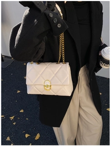 Close-up of white quilted crossbody bag featuring a gold twist lock and chain strap