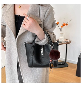 Detail of black lychee grain leather bucket bag with fur charm and silver metal hardware