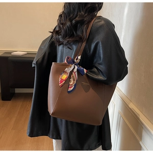 Detail of dark brown leather tote bag with printed silk scarf on handle and shoulder strap