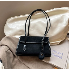 Macro detail of black vintage underarm bag featuring suede and patent leather textures