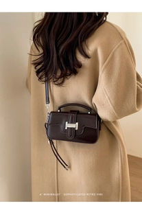 Detail of dark brown retro crossbody bag with silver H-buckle on camel cashmere coat
